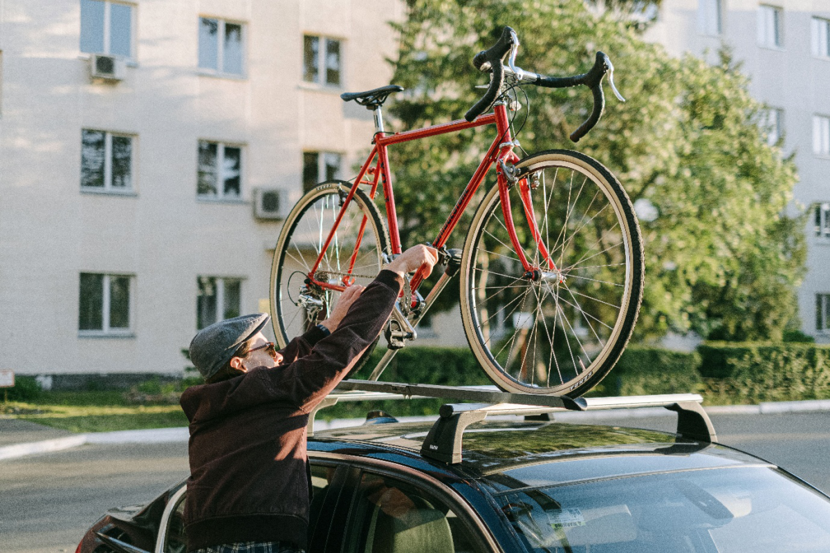 A person using a car to transport a bike